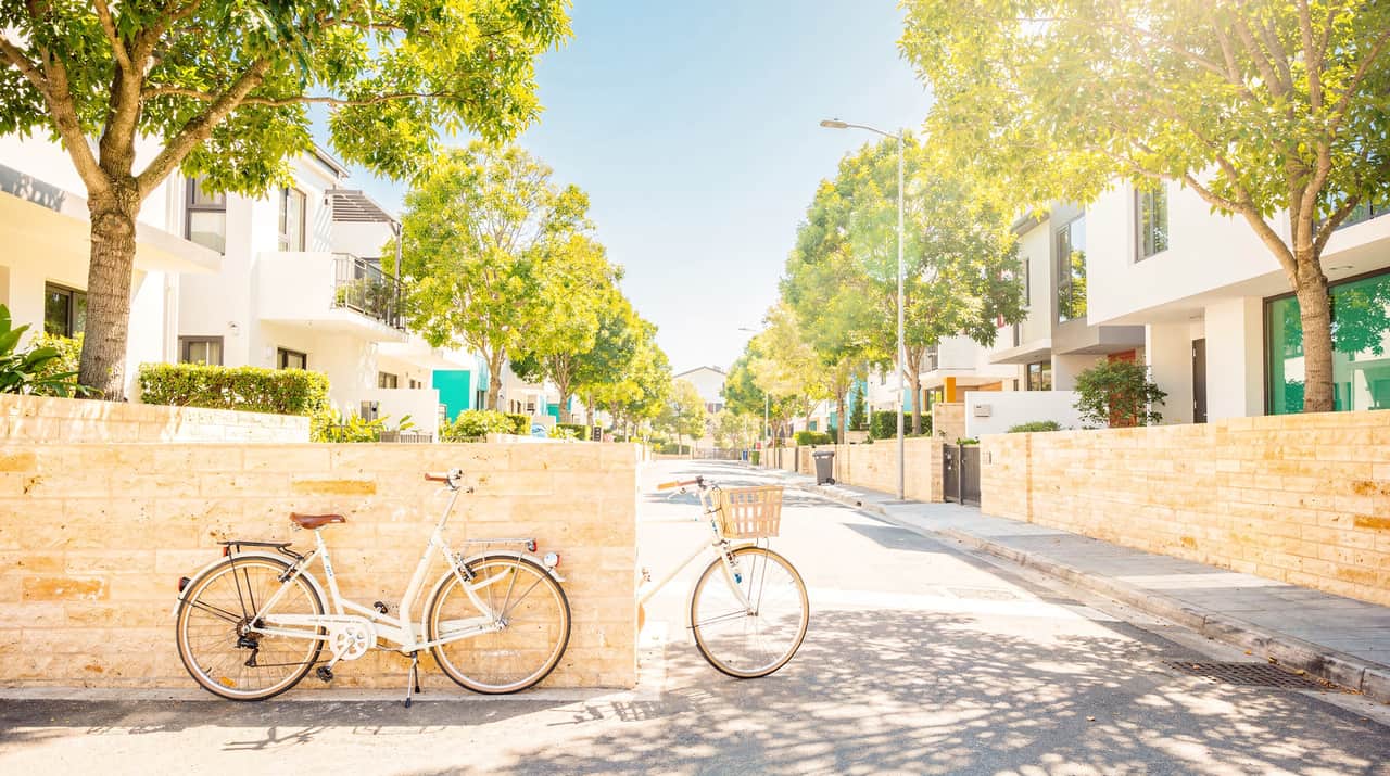 En cykel lutad mot en tegelvägg på en solig gata en klar morgon, med staden som öppnar sig framåt